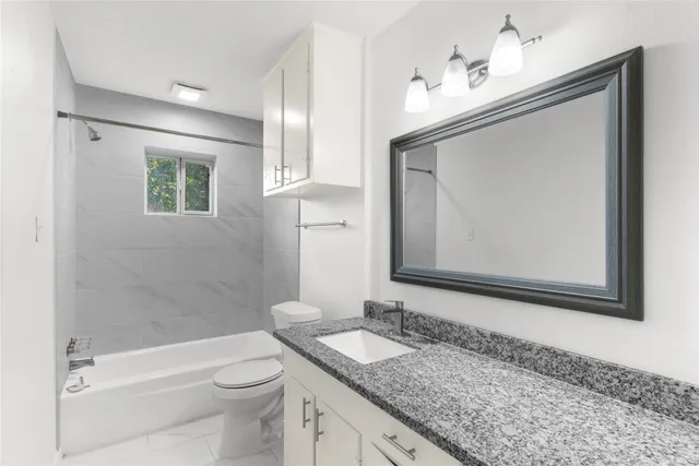 a bathroom with a granite countertop sink a toilet and a mirror