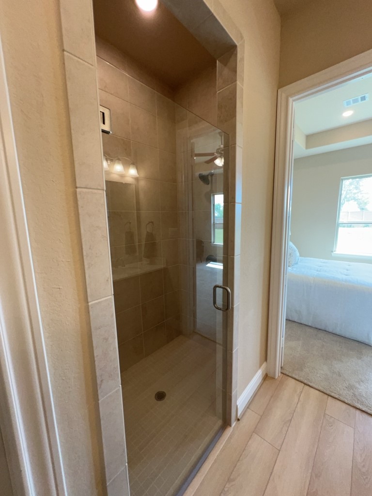5602 Caracara Street Manvel, TX 77578 - Photo 16 of 27 a bathroom with a glass door shower a sink and a mirror