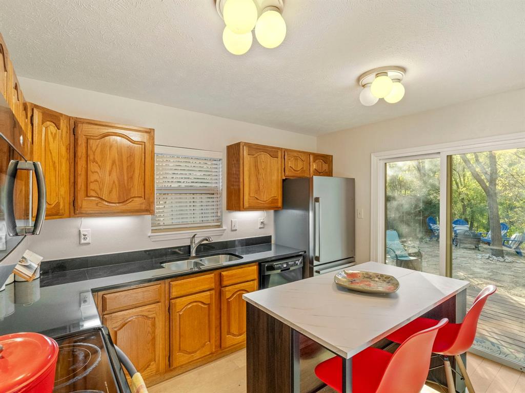 13347 Pandora Circle Dallas, TX 75238 - Photo 9 of 36 a kitchen with stainless steel appliances granite countertop a sink a stove a refrigerator a dining table and chairs with wooden floor