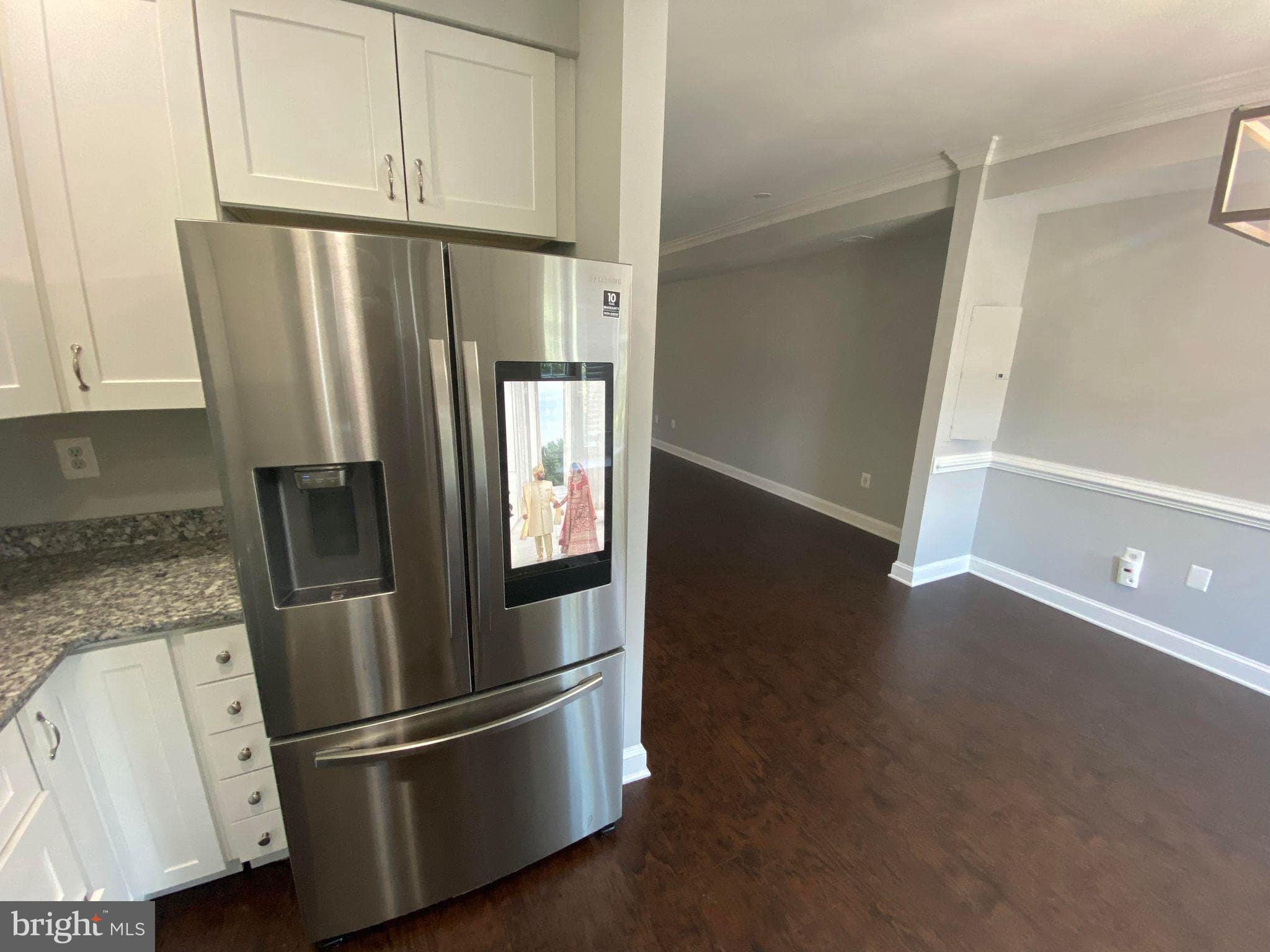 2256 South Garfield Street, Unit 11 Arlington, VA 22206 - Photo 8 of 21 a view of a refrigerator in kitchen and an empty room with wooden floor