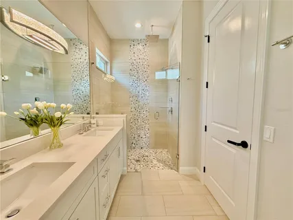 a spacious en suite bathroom with a double vanity sink a mirror and a shower