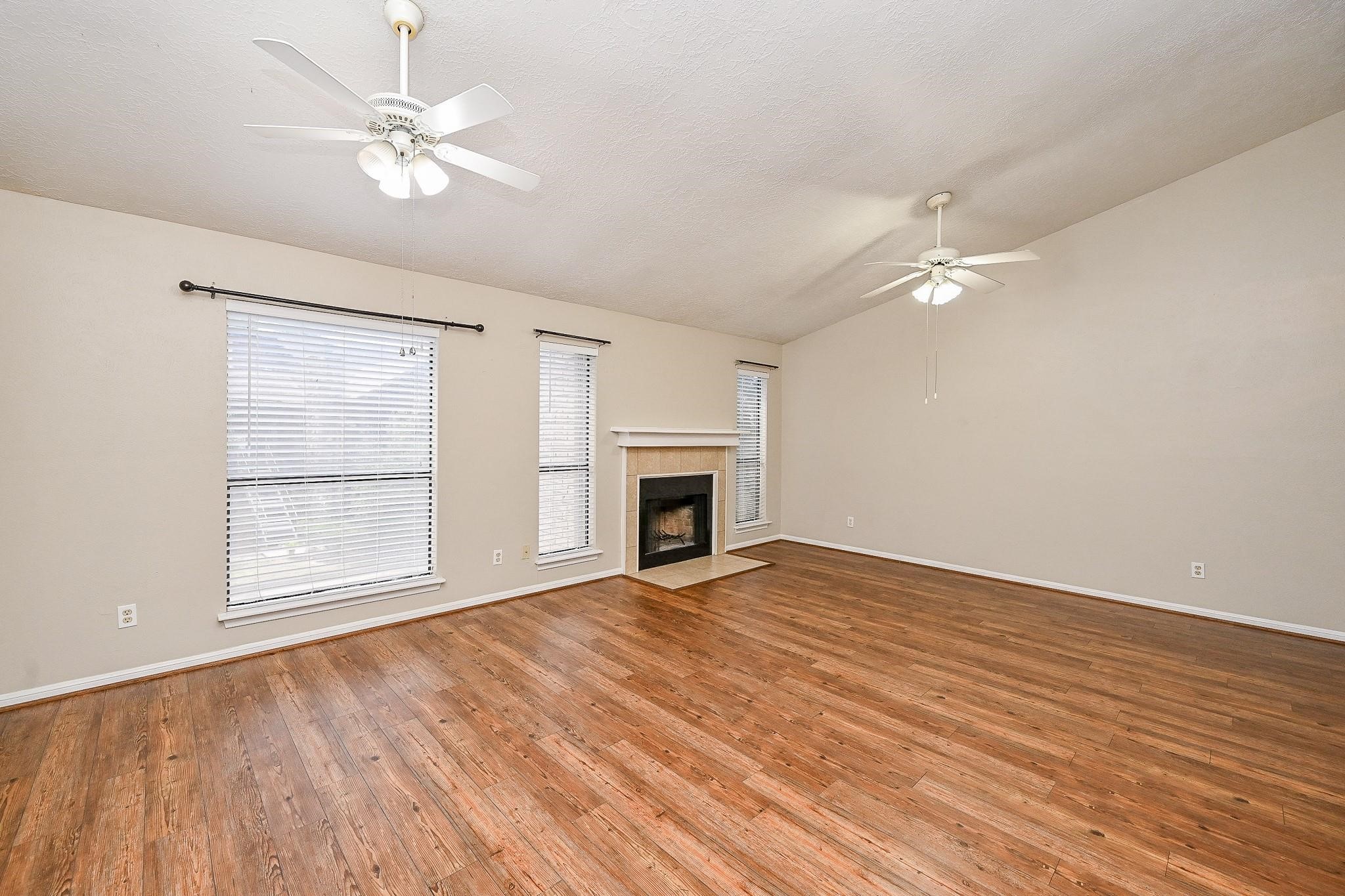 12755 Mill Ridge Drive, Unit 217 Cypress, TX 77429 - Photo 2 of 17 wooden floor fireplace and windows in an empty room
