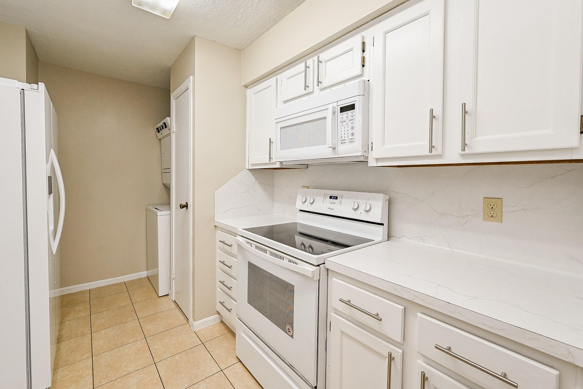 12755 Mill Ridge Drive, Unit 217 Cypress, TX 77429 - Photo 5 of 17 a kitchen with white cabinets and white appliances