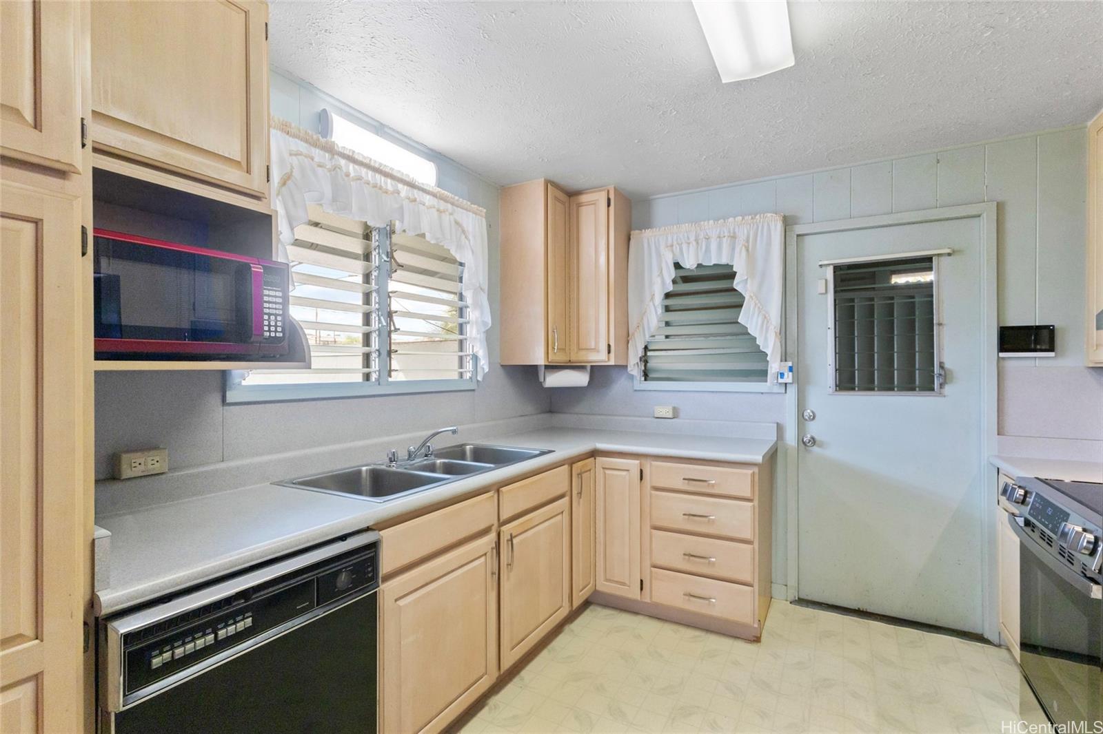 94-341 Kahuanani Street Waipahu, HI 96797 - Photo 7 of 24 a kitchen with white cabinets and appliances