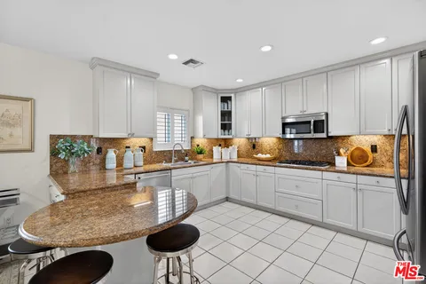a kitchen with stainless steel appliances granite countertop a stove a sink and a refrigerator