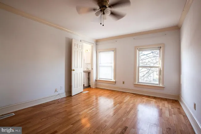 a view of an empty room with a window and wooden floor