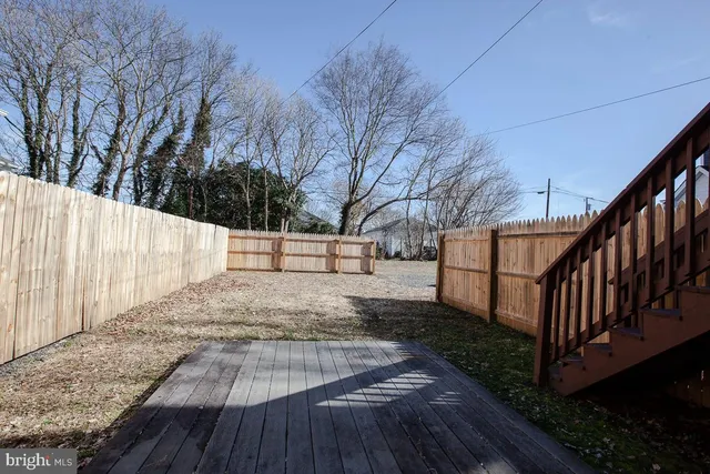 a view of backyard with wooden floor and fence