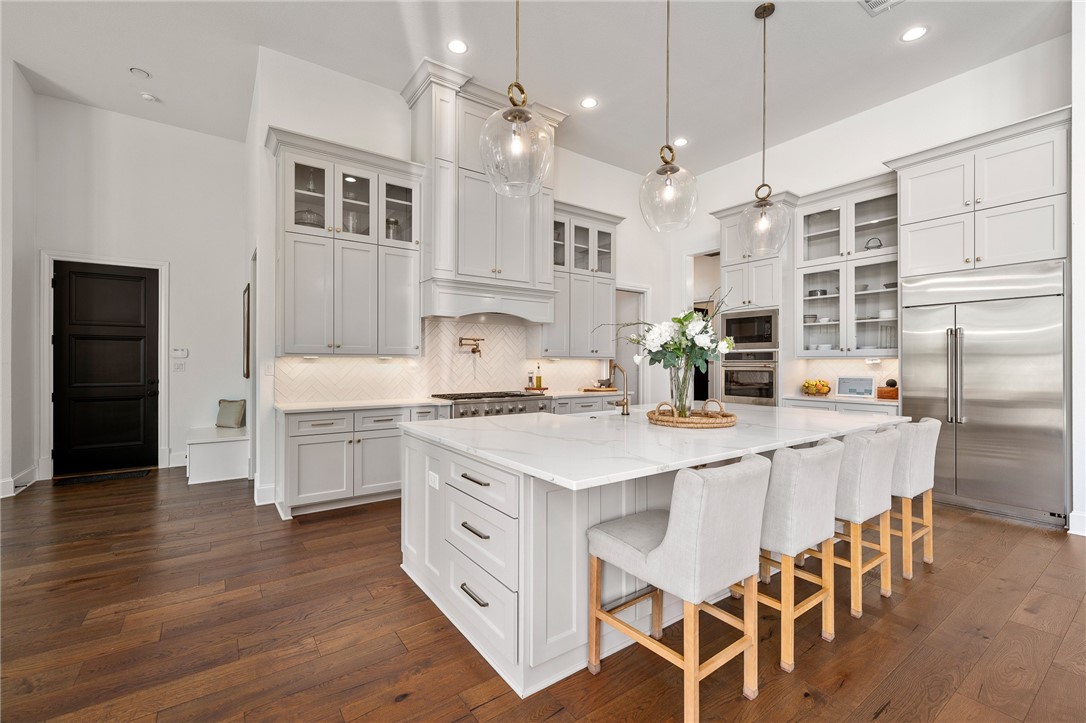 1351 River Road Waco, TX 76705 - Photo 5 of 96 a kitchen with stainless steel appliances kitchen island granite countertop a wooden floor and white cabinets
