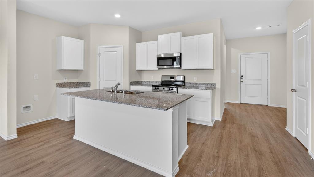 1683 Mantle Road Crandall, TX 75114 - Photo 2 of 31 Kitchen featuring a central island with an undermount sink, granite countertops, white cabinetry, stainless steel appliances, and wood-finish flooring