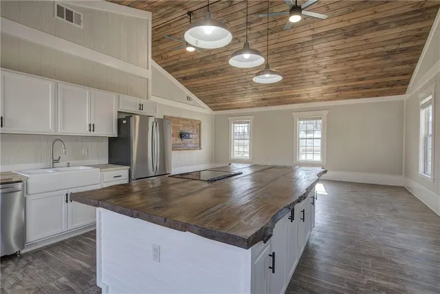 a kitchen with stainless steel appliances granite countertop a sink and cabinets with wooden floor