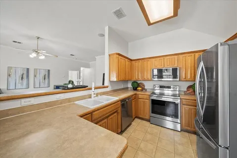 a large kitchen with stainless steel appliances granite countertop a refrigerator and a sink