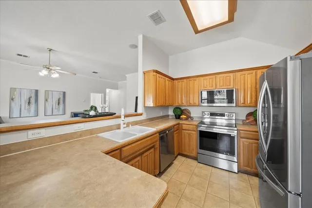 a large kitchen with stainless steel appliances granite countertop a refrigerator and a sink