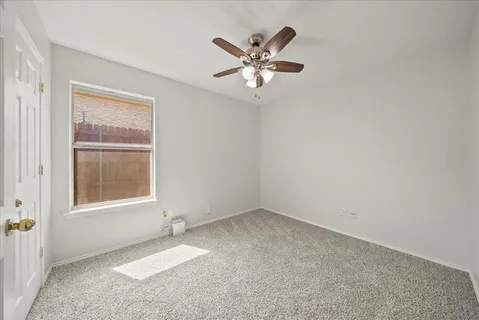 an empty room with windows and ceiling fan
