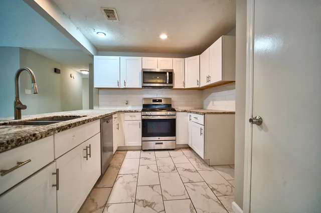 a kitchen with granite countertop a stove top oven sink and cabinets