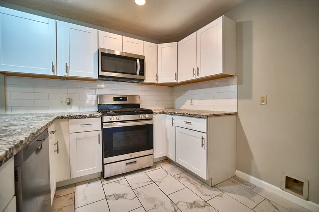 a kitchen with granite countertop white cabinets stainless steel appliances and a sink