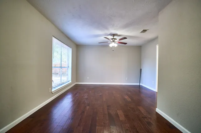 a view of an empty room with wooden floor and a window