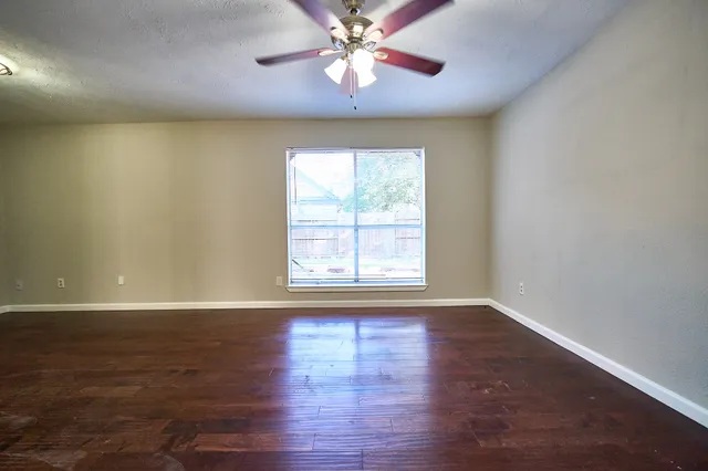 a view of an empty room with window and wooden floor