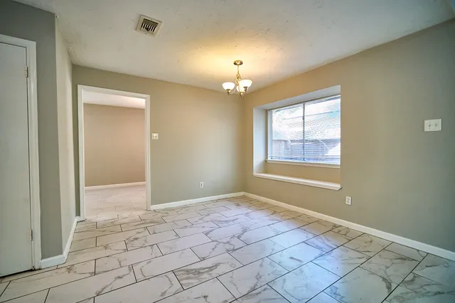 a view of an empty room with window and chandelier fan
