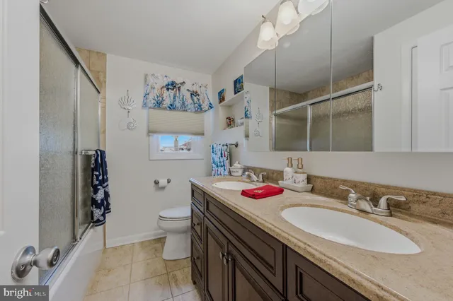 a bathroom with a granite countertop sink vanity mirror and toilet