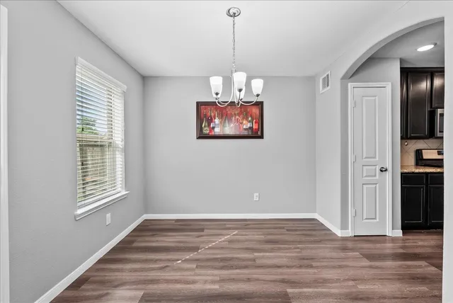 a view of an empty room with window and wooden floor