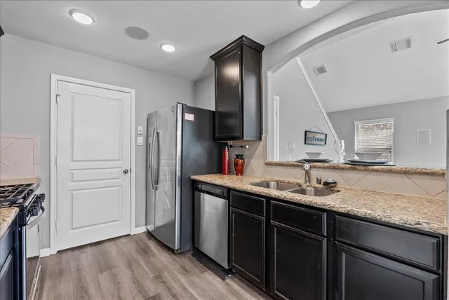 a kitchen with a sink a refrigerator and wooden floor