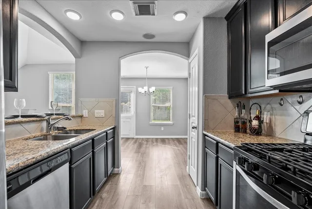 a kitchen with granite countertop stainless steel appliances a sink stove and cabinets