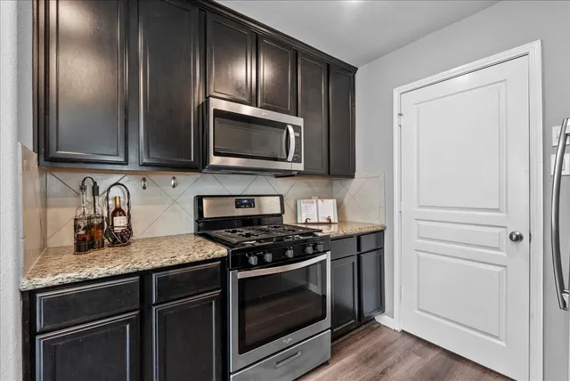 a kitchen with granite countertop cabinets stainless steel appliances and wooden floor