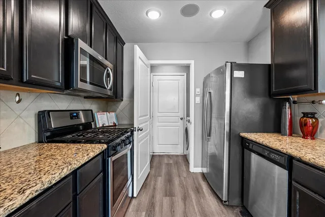 a kitchen with stainless steel appliances granite countertop a refrigerator a stove and a sink