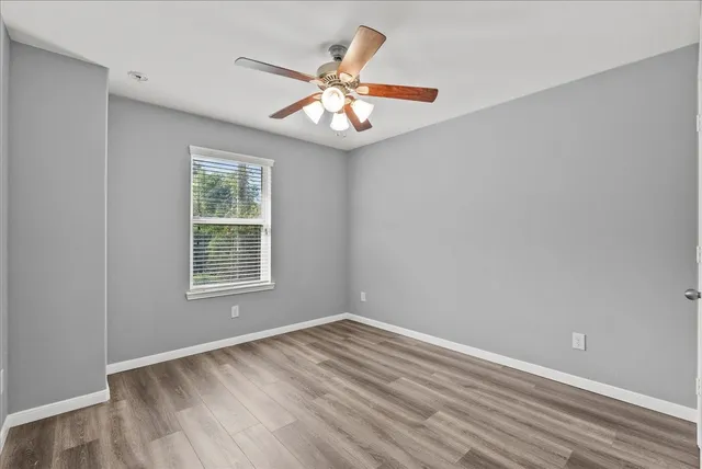 an empty room with window and chandelier fan