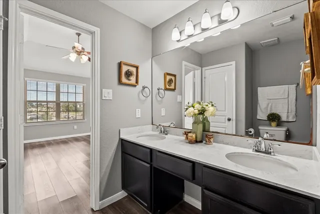 a bathroom with double vanity sinks a vanity a lamp and a mirror