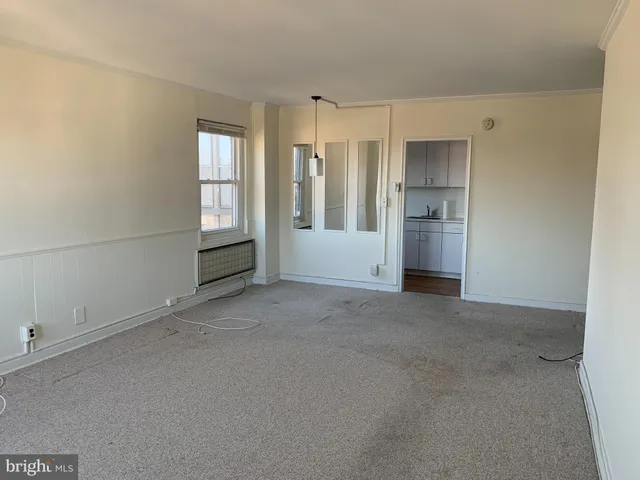 a view of empty room with kitchen and window