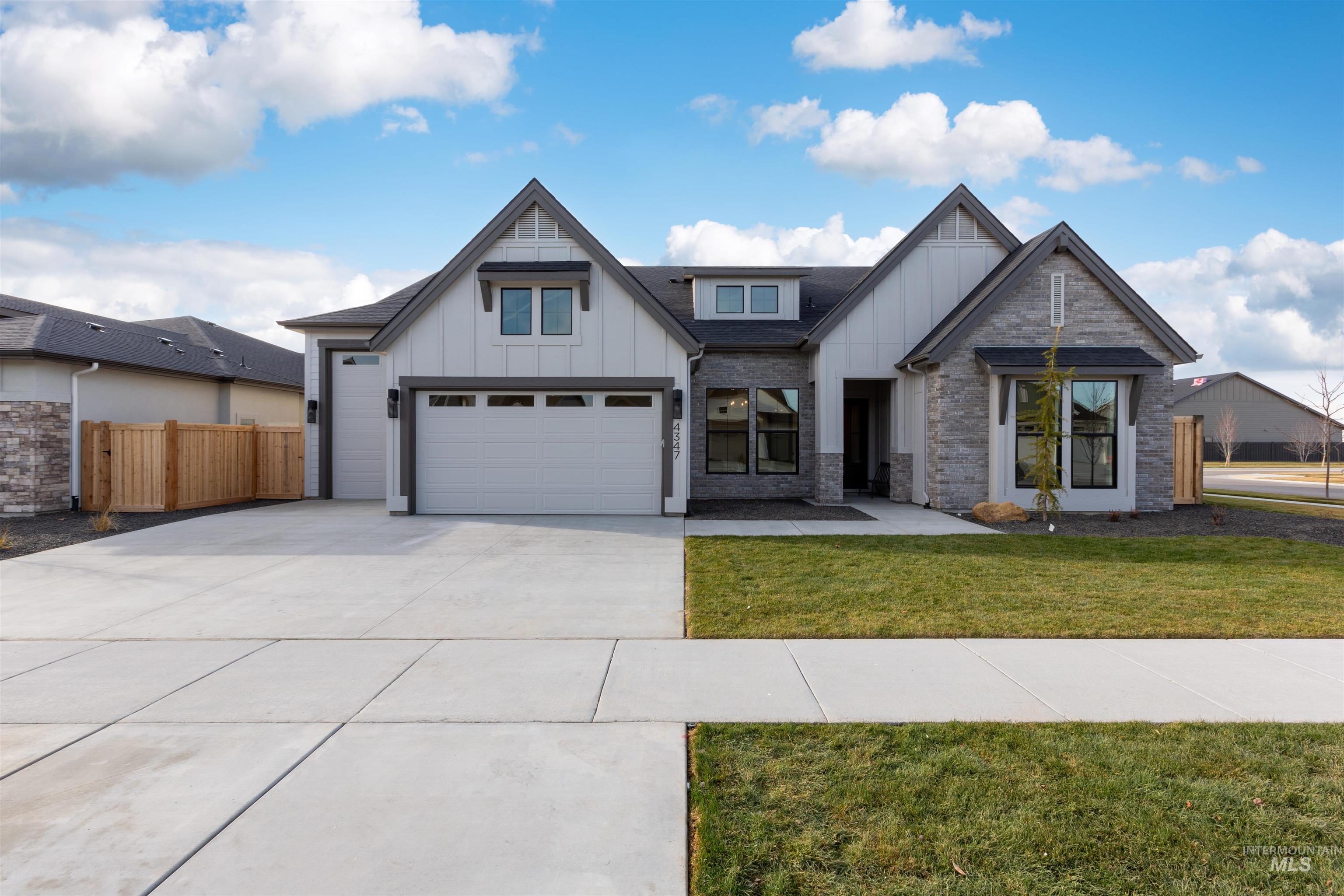 Modern farmhouse with board and batten siding, a garage, and concrete driveway