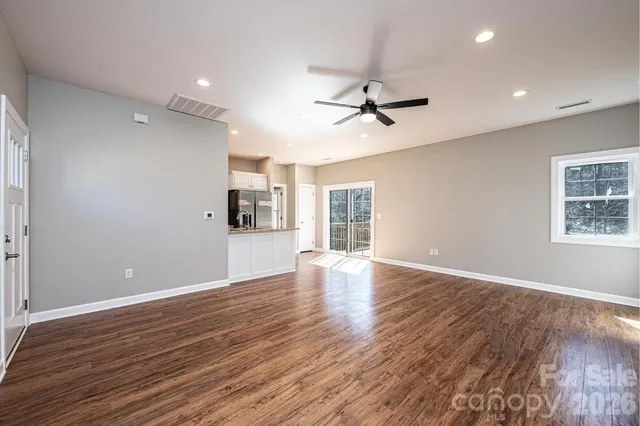 a view of empty room with wooden floor and ceiling fan