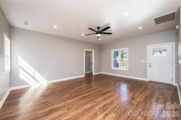 a view of an empty room with a window and wooden floor