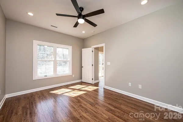 an empty room with wooden floor and windows