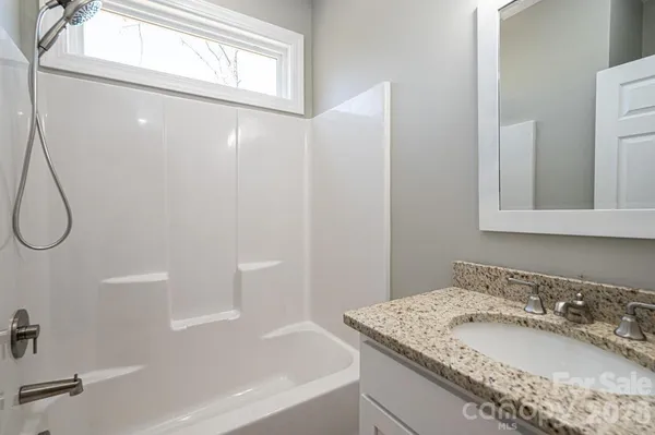 a bathroom with a granite countertop sink a mirror and a bathtub