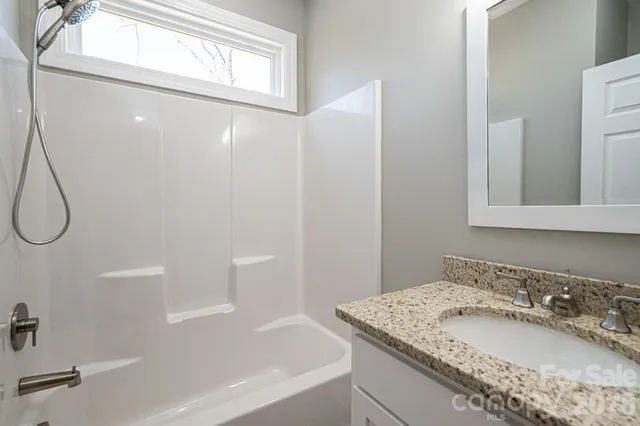 a bathroom with a granite countertop sink a mirror and a bathtub