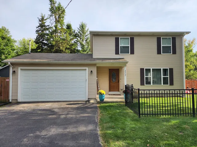 a view of a house with a yard and a large tree