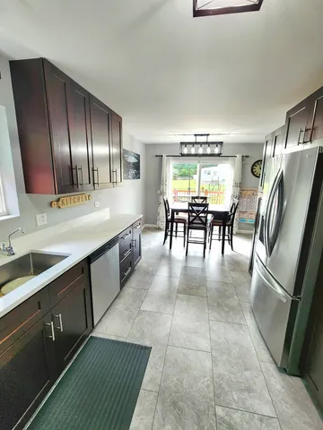 a dining hall with granite countertop a refrigerator a stove top oven a sink and dishwasher