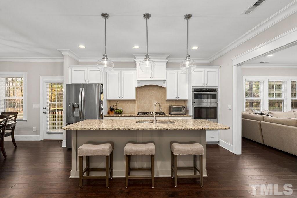 1217 Harrison Ridge Road Wake Forest, NC 27587 - Photo 8 of 30 a kitchen with stainless steel appliances granite countertop a table chairs stove and wooden floor