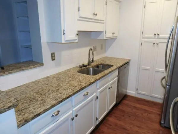 a kitchen with granite countertop a sink and a refrigerator