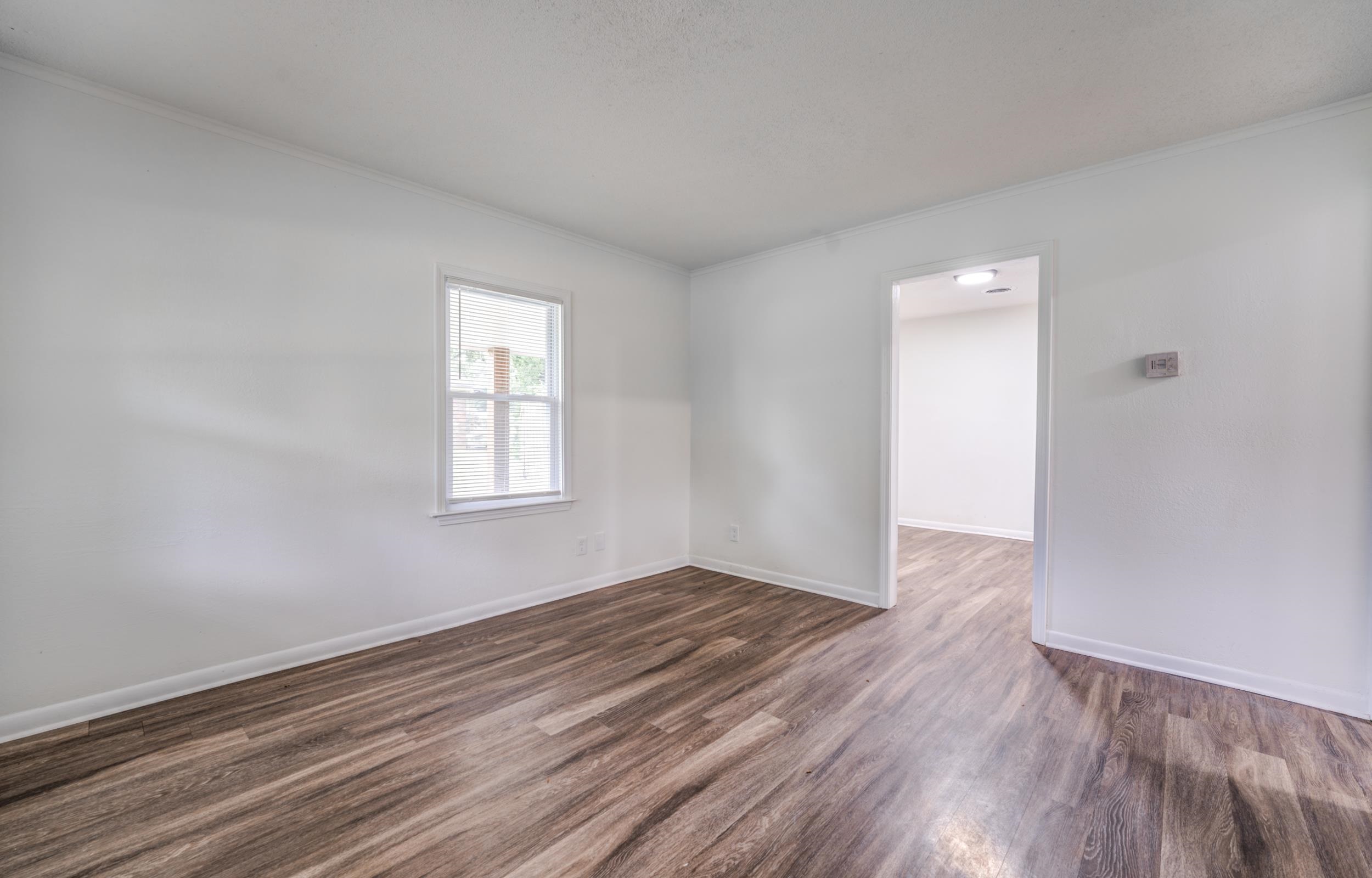 5341 Millbranch Road Memphis, TN 38116 - Photo 4 of 29 a view of an empty room with wooden floor and a window
