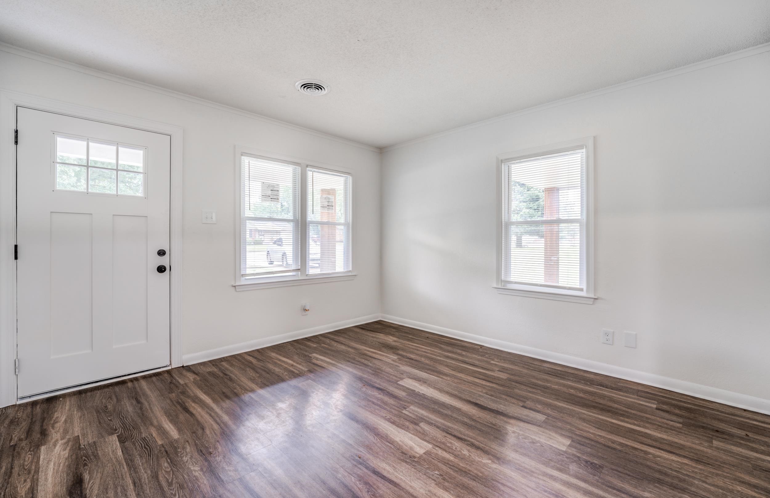 5341 Millbranch Road Memphis, TN 38116 - Photo 7 of 29 an empty room with wooden floor and windows