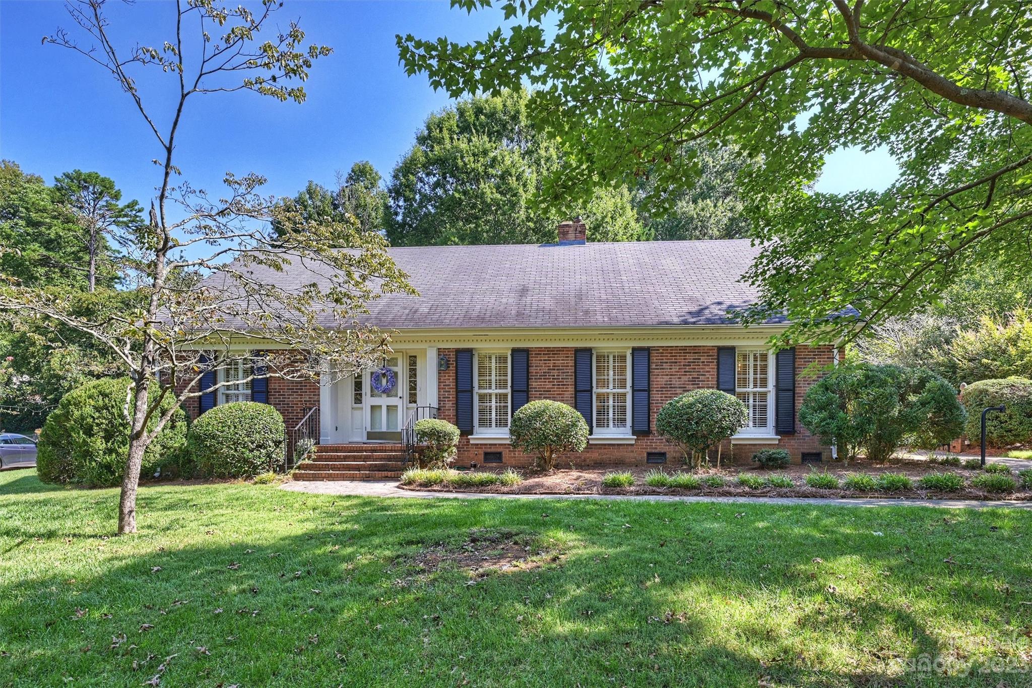 a front view of a house with garden and trees