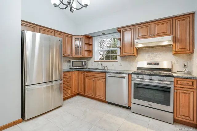 a kitchen with granite countertop stainless steel appliances a refrigerator a sink and cabinets