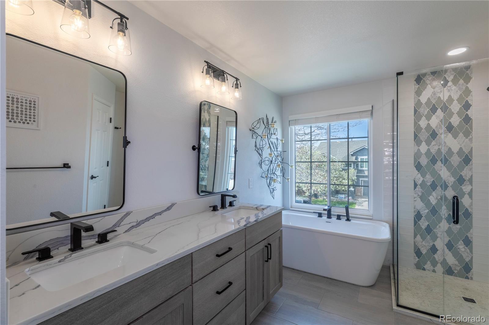 294 West Willowick Circle Highlands Ranch, CO 80129 - Photo 13 of 37 a bathroom with double vanity sink a mirror a bathtub and next to a window