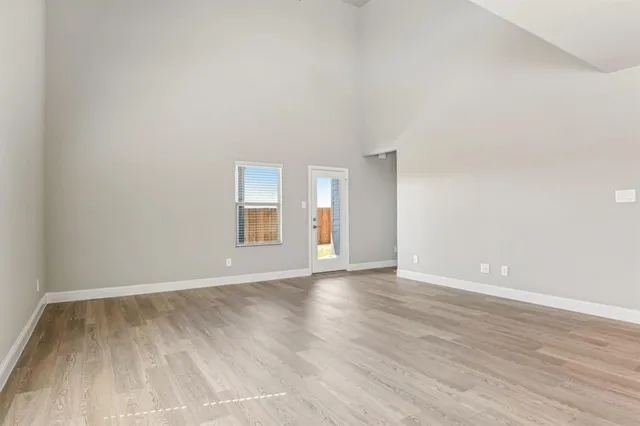 a view of an empty room and window and wooden floor