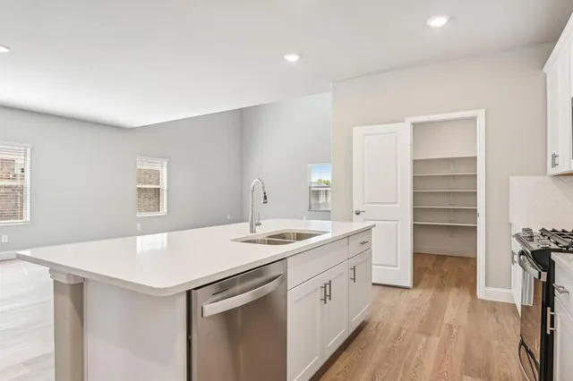 a kitchen with a sink a stove cabinets and wooden floor