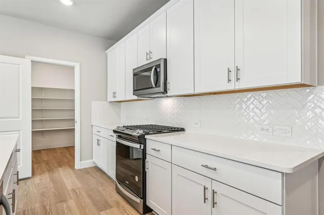 a kitchen with granite countertop white cabinets and stainless steel appliances