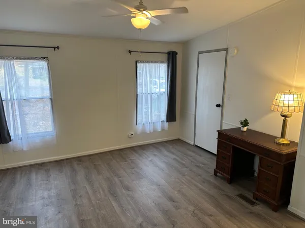 a view of an empty room with window and wooden floor